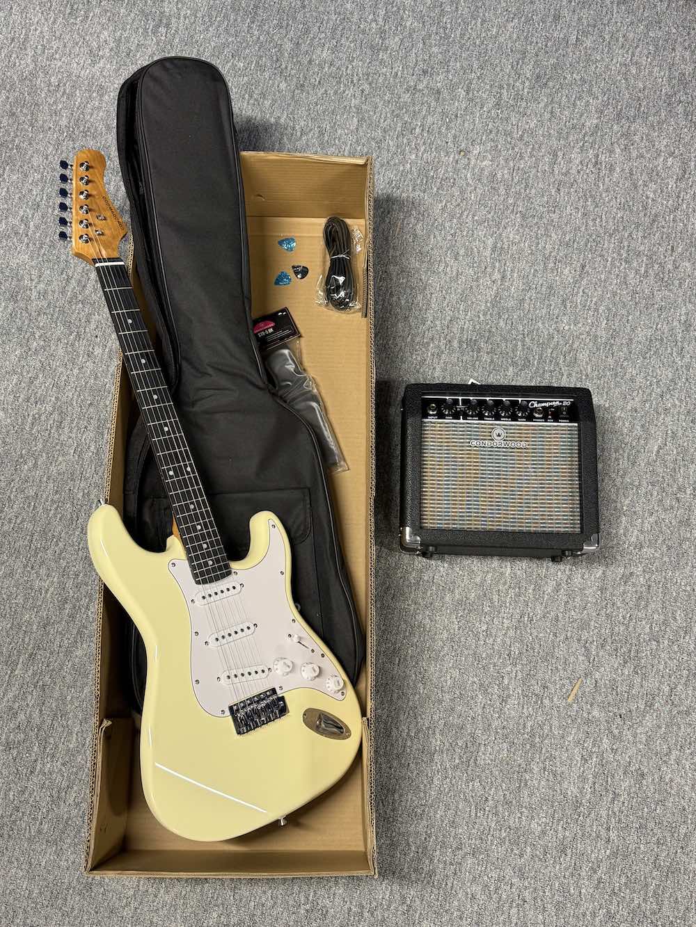 Flat-lay photo of the RS-100 Starter Pack showing guitar, amplifier, gig bag, strap, and cable.